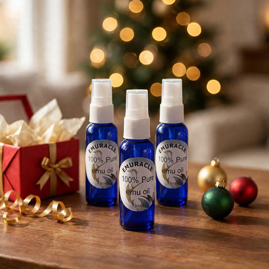 Emuracle Stocking Stuffer 3-Pack: three 30 ml emu oil spray bottles by a Christmas tree and an open gift
